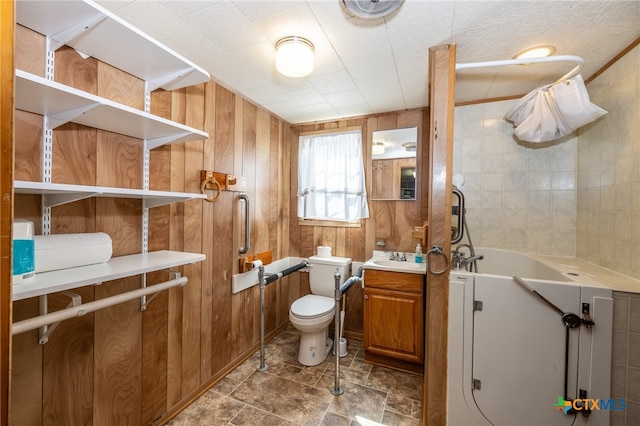 bathroom with a bathing tub, wood walls, toilet, and vanity