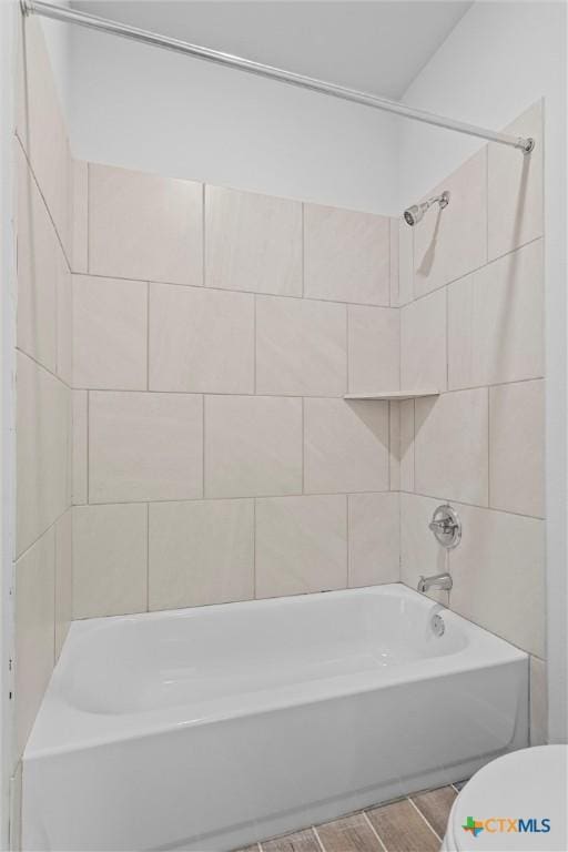 bathroom with tiled shower / bath combo and toilet