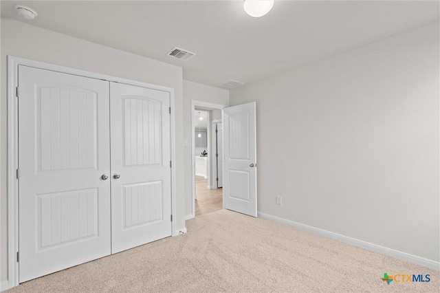 unfurnished bedroom featuring light carpet and a closet