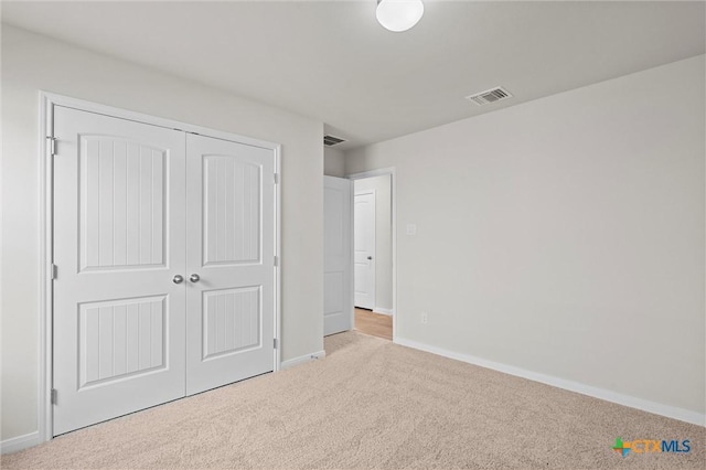 unfurnished bedroom with light colored carpet and a closet