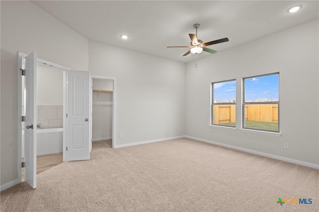 unfurnished bedroom featuring a spacious closet, light carpet, and ceiling fan