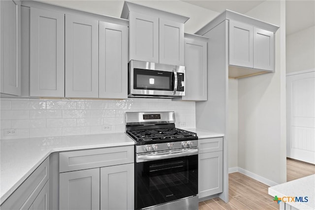 kitchen featuring tasteful backsplash, appliances with stainless steel finishes, and light hardwood / wood-style flooring