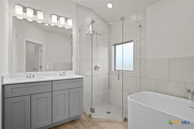 bathroom featuring plus walk in shower, tile walls, and vanity