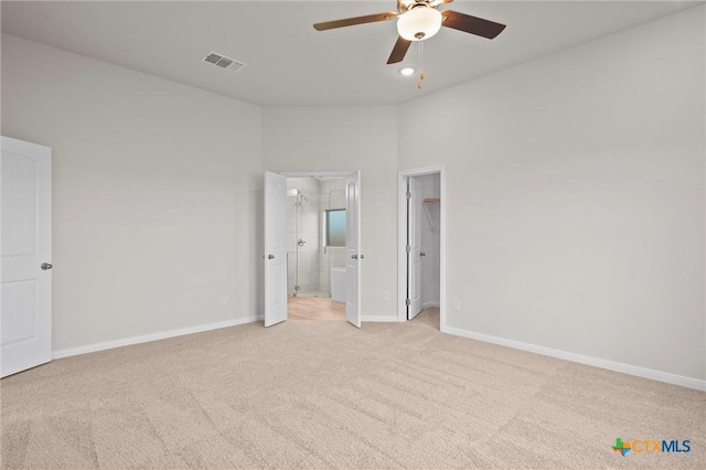 unfurnished bedroom with light carpet, connected bathroom, a spacious closet, and ceiling fan