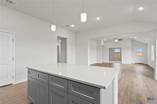 kitchen with pendant lighting, gray cabinets, ceiling fan, light hardwood / wood-style floors, and vaulted ceiling