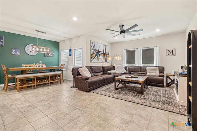 living area with baseboards, recessed lighting, light tile patterned flooring, and ceiling fan with notable chandelier