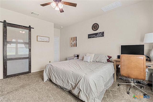 carpeted bedroom featuring a barn door, baseboards, ceiling fan, and visible vents