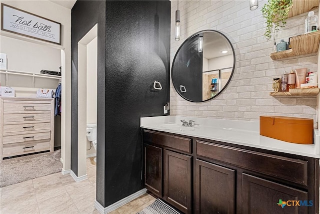 bathroom with a spacious closet, tile patterned flooring, toilet, vanity, and baseboards