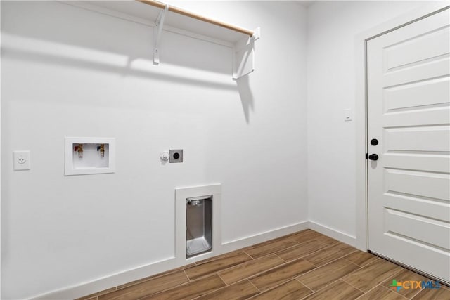 clothes washing area with wood finish floors, washer hookup, electric dryer hookup, laundry area, and baseboards