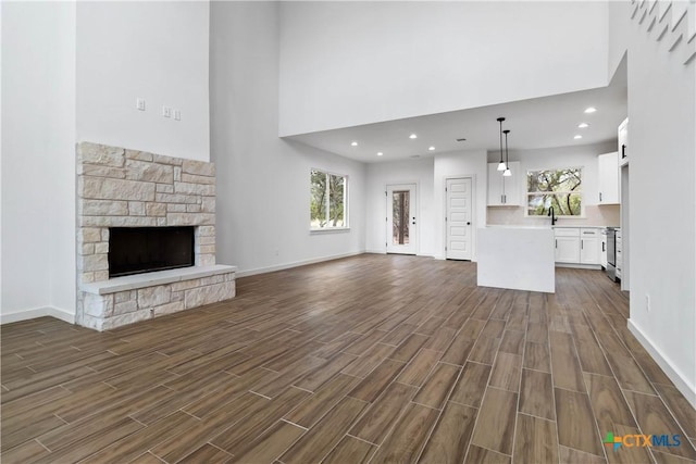 unfurnished living room featuring sink, a wealth of natural light, and a fireplace