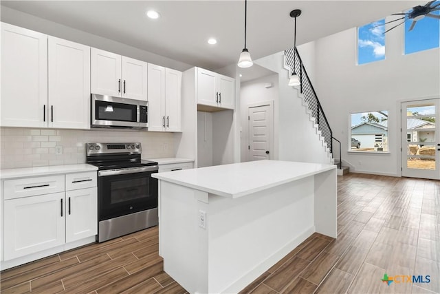 kitchen featuring white cabinetry, pendant lighting, a kitchen island, and appliances with stainless steel finishes