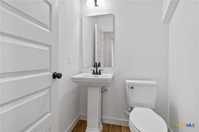 bathroom with hardwood / wood-style flooring and toilet