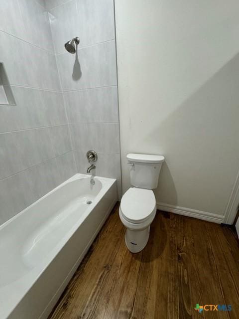 bathroom with tiled shower / bath, wood-type flooring, and toilet