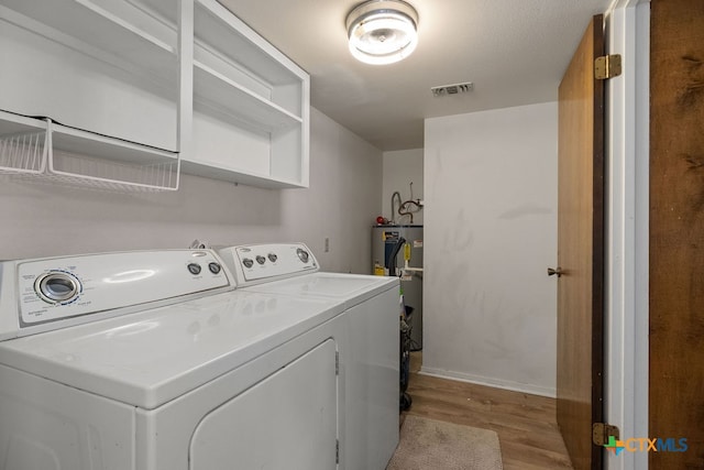 laundry room with electric water heater, light hardwood / wood-style floors, and separate washer and dryer