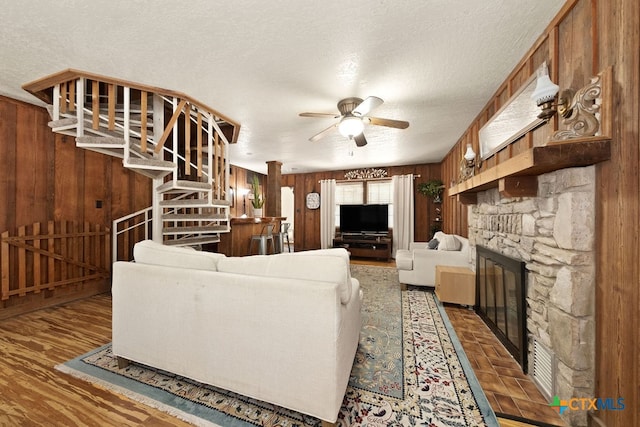 living room with wood-type flooring, a textured ceiling, and wooden walls