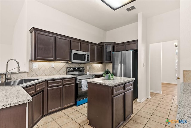 kitchen with dark brown cabinetry, sink, light tile patterned floors, and appliances with stainless steel finishes