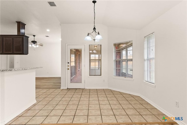 unfurnished dining area featuring light tile patterned flooring and ceiling fan with notable chandelier