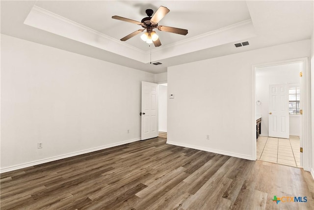 unfurnished room featuring a tray ceiling, ceiling fan, crown molding, and dark hardwood / wood-style floors