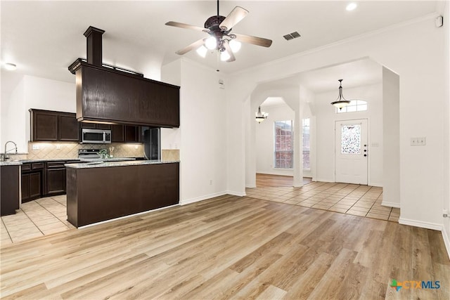 kitchen with light wood-type flooring, dark brown cabinetry, stainless steel appliances, ceiling fan, and sink