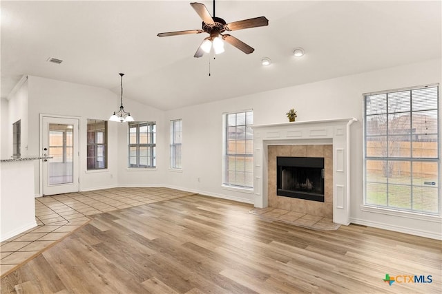 unfurnished living room featuring light hardwood / wood-style flooring, a wealth of natural light, and a tiled fireplace