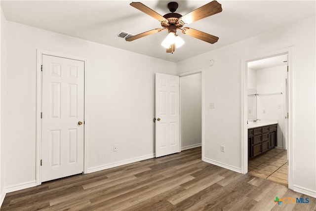 unfurnished bedroom featuring dark hardwood / wood-style floors, ceiling fan, and ensuite bath