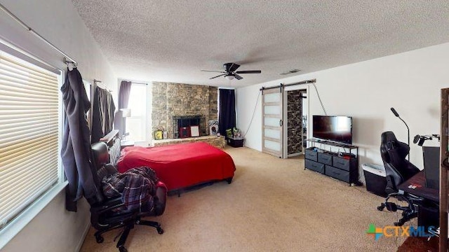 2011 Valley Oaks Dr, Harker Heights, TX 76548 - carpeted bedroom featuring a textured ceiling, a fireplace, ceiling fan, and a barn door
