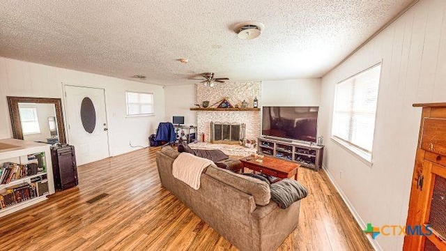 2011 Valley Oaks Dr, Harker Heights, TX 76548 - living area with wood finished floors, a large fireplace, a textured ceiling, and a ceiling fan