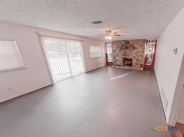 unfurnished living room featuring a fireplace, a textured ceiling, concrete floors, and ceiling fan