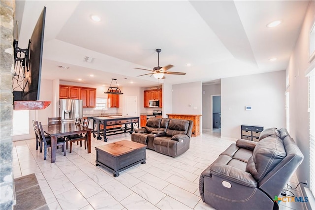 living area with visible vents, a tray ceiling, ceiling fan, and recessed lighting