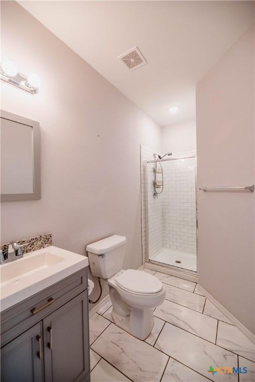 bathroom featuring toilet, vanity, visible vents, marble finish floor, and a stall shower