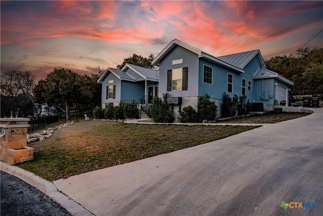 view of front of home featuring stucco siding, concrete driveway, an attached garage, a standing seam roof, and fence