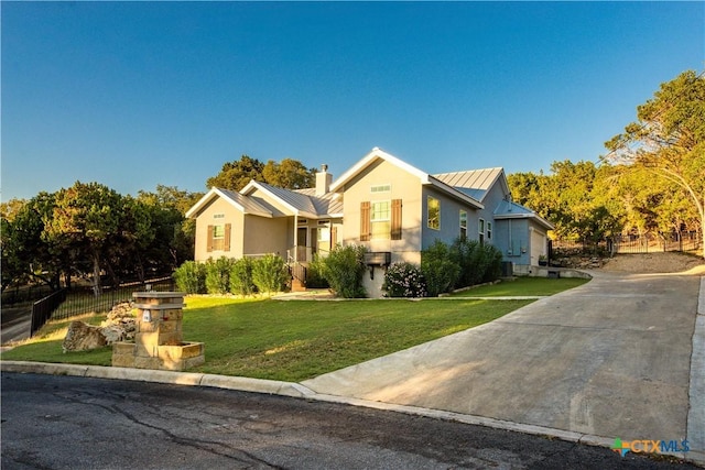 view of front of property featuring metal roof, fence, stucco siding, a standing seam roof, and a front yard