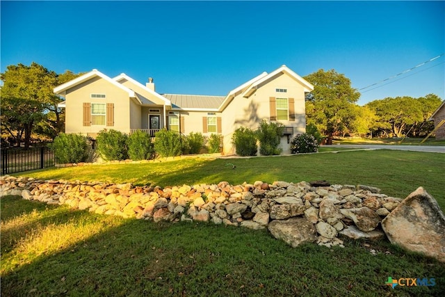 view of front facade featuring metal roof, a front lawn, a chimney, and fence