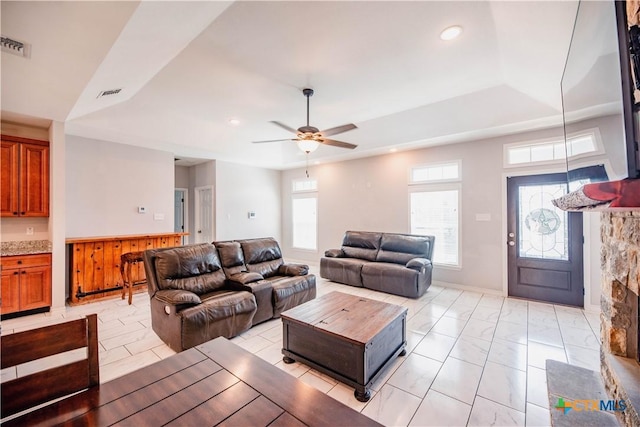 living room featuring a ceiling fan, visible vents, a tray ceiling, and recessed lighting