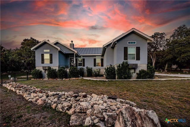 view of front of home featuring metal roof, fence, a lawn, a standing seam roof, and a chimney