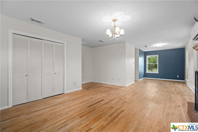 interior space featuring light wood-type flooring, a notable chandelier, and a textured ceiling