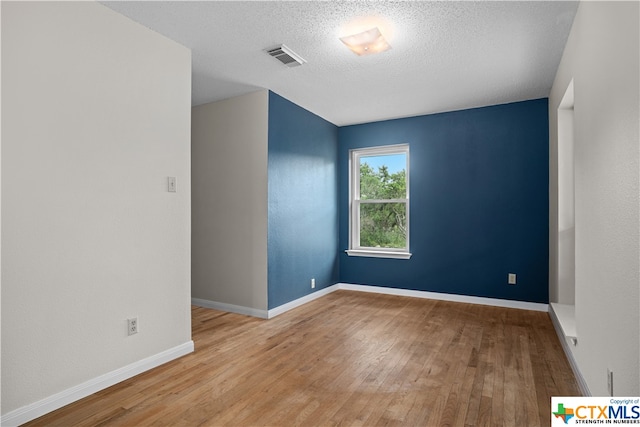 spare room with a textured ceiling and light hardwood / wood-style flooring