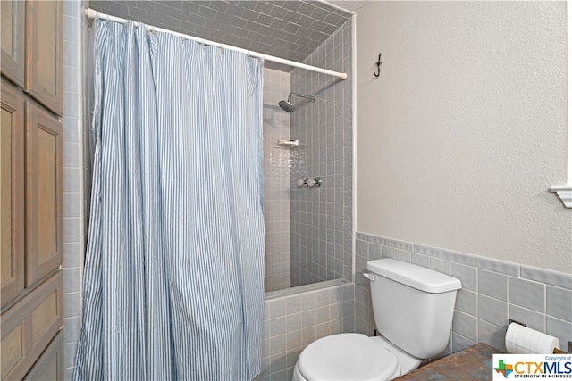 bathroom with toilet, tile walls, and shower / bath combo with shower curtain