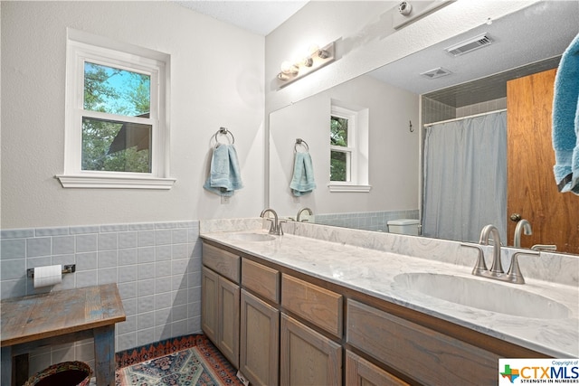 bathroom with a healthy amount of sunlight, toilet, and tile walls