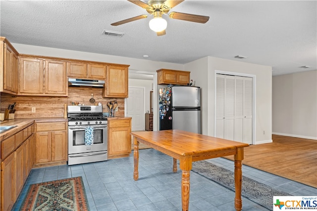 kitchen featuring light hardwood / wood-style flooring, ceiling fan, ventilation hood, backsplash, and appliances with stainless steel finishes