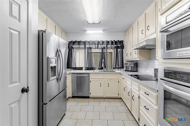 205 Magdalena Dr, Victoria, TX 77904 - kitchen featuring light countertops, a textured ceiling, stainless steel appliances, light tile patterned floors, and under cabinet range hood