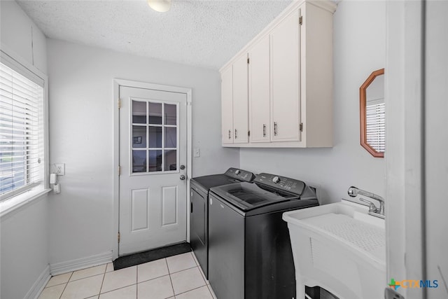 205 Magdalena Dr, Victoria, TX 77904 - laundry area featuring washer and dryer, cabinet space, a sink, a textured ceiling, and light tile patterned floors