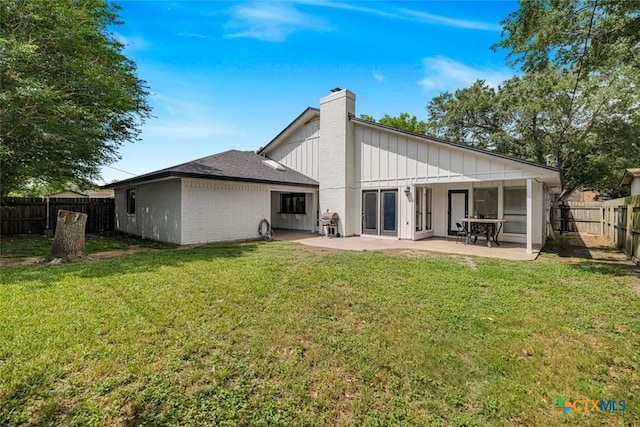 205 Magdalena Dr, Victoria, TX 77904 - back of property with a patio, a fenced backyard, a chimney, board and batten siding, and a lawn