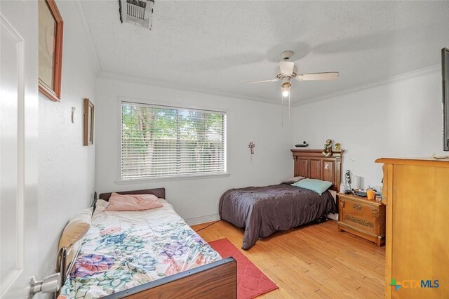 205 Magdalena Dr, Victoria, TX 77904 - bedroom featuring a ceiling fan, a textured ceiling, visible vents, crown molding, and light wood-style flooring