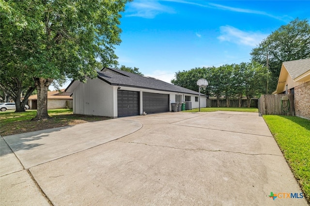 205 Magdalena Dr, Victoria, TX 77904 - view of property exterior with driveway, fence, roof mounted solar panels, a yard, and an attached garage