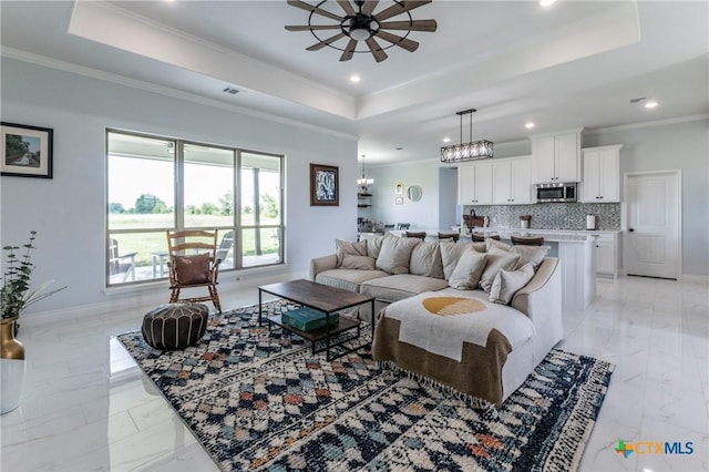 living room featuring baseboards, visible vents, a raised ceiling, and crown molding