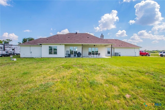 back of property with a yard, a patio, and a chimney