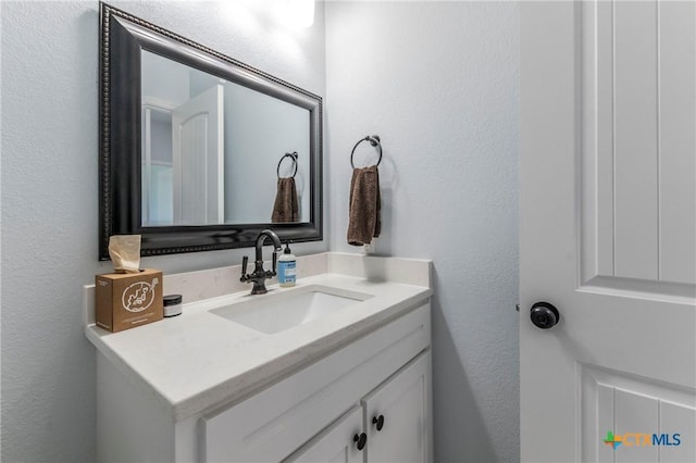 bathroom with a textured wall and vanity