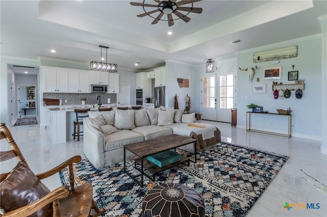 living room with ornamental molding, a raised ceiling, visible vents, and marble finish floor