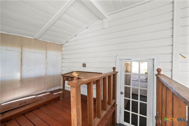 staircase with wooden walls, wood-type flooring, and vaulted ceiling